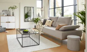 Salon moderne au style épuré avec canapé gris, table basse noire et meuble blanc.