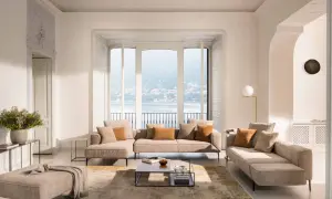 Salon lumineux avec canapé modulable, pouf et table basse, dans un style design scandinave épuré. Vue sur un lac.