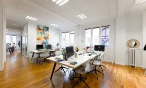 Un bureau moderne avec des postes de travail, des ordinateurs et une décoration murale colorée. L'accueil du bureau est bien organisé pour le planning.