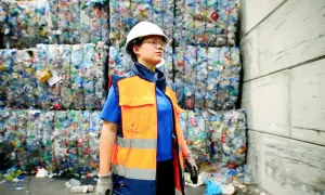 Employée en tenue de sécurité, devant des balles de plastique compressé. Elle veille au respect de la réglementation locale sur les déchets, en accord avec le code du travail.