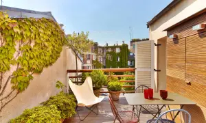 Une belle idee amenagement terrasse : mobilier coloré, plantes luxuriantes et vue sur les toits. Parfait pour un moment de détente.