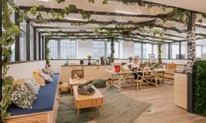 Aménagement locaux start up : un espace de travail lumineux et végétalisé, avec une femme travaillant à son bureau.