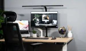 Bureau moderne pour aménager un espace de télétravail ergonomique. Ordinateur portable, écran, clavier, souris, et lampe de bureau.
