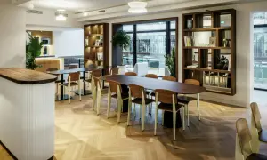 Aménagement locaux professionnels : espace lumineux avec tables, chaises en bois et étagères murales.