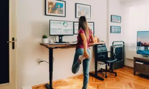 Une femme s'étire à son bureau debout, une idée pour comment orienter son bureau pour plus de bien-être.