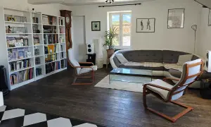 Salon moderne avec bibliothèque, canapé, table basse et fauteuils. Une démarche ergonomique pour un confort optimal.