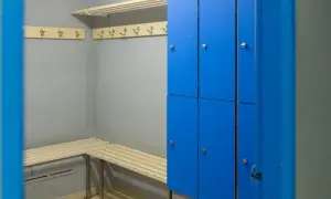 Vestiaire d'entreprise avec casiers personnels bleus, bancs en bois et patères.