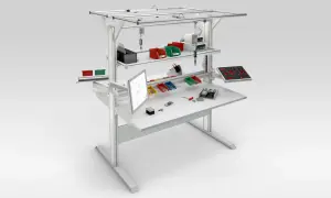 Poste aménagé avec écran, bacs de rangement colorés, outils et composants pour un travail organisé.