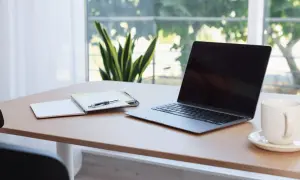 Bureau avec ordinateur portable, carnet et stylo. L'obligation employeur fournir ordinateur est respectée.