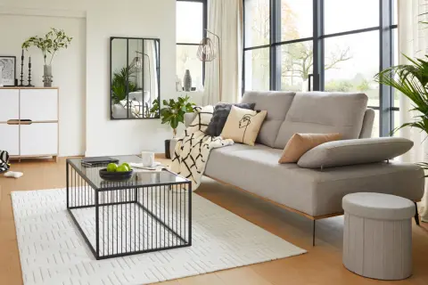 Salon moderne au style épuré avec canapé gris, table basse noire et meuble blanc.
