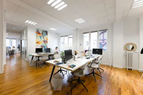 Un bureau moderne avec des postes de travail, des ordinateurs et une décoration murale colorée. L'accueil du bureau est bien organisé pour le planning.