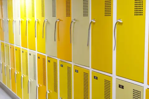 Rangée de casiers jaunes et beiges, numérotés, conformes au vestiaire code du travail.