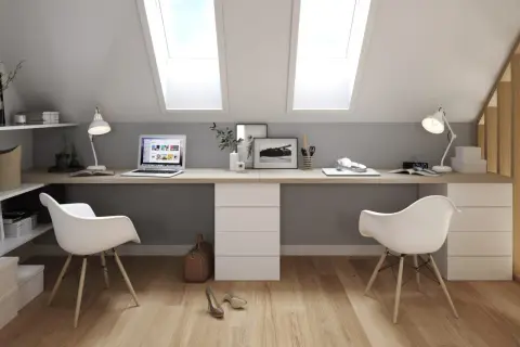 Deux bureaux modernes, dos à dos, sous des fenêtres de toit. L'espace de travail est lumineux et fonctionnel.