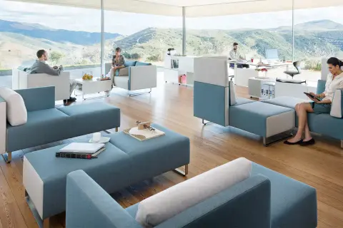 Un espace convivialité entreprise moderne avec des sièges modulables bleus et blancs, offrant une vue panoramique sur des collines verdoyantes.