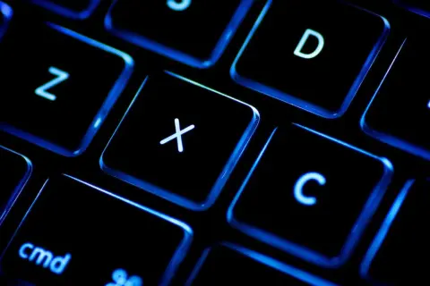 Gros plan sur un clavier rétroéclairé, les touches noires illuminées de bleu. On distingue les lettres Z, X, C, D et la touche "cmd". Un clavier BÉPO pour une frappe optimisée.