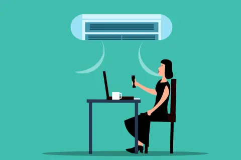 Une femme ajuste la climatisation de son bureau, cherchant la température idéale pour respecter le code du travail.
