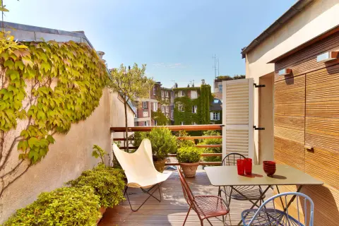 Une belle idee amenagement terrasse : mobilier coloré, plantes luxuriantes et vue sur les toits. Parfait pour un moment de détente.