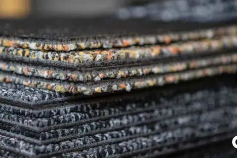 Échantillons de moquette empilés, montrant la texture et les couleurs variées. Une vision claire de la durée de vie d'une moquette.