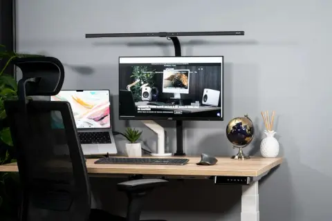 Bureau moderne pour aménager un espace de télétravail ergonomique. Ordinateur portable, écran, clavier, souris, et lampe de bureau.