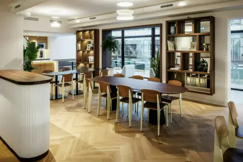 Aménagement locaux professionnels : espace lumineux avec tables, chaises en bois et étagères murales.