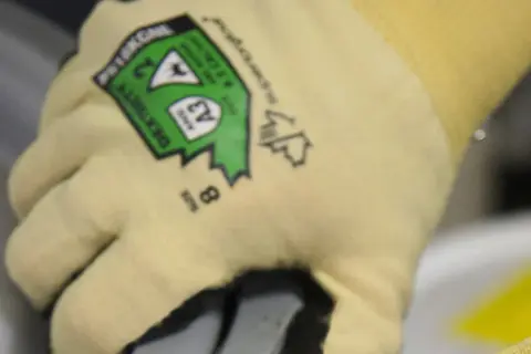 Gant de protection jaune avec étiquette verte indiquant le type de gants de protection et la taille 8.