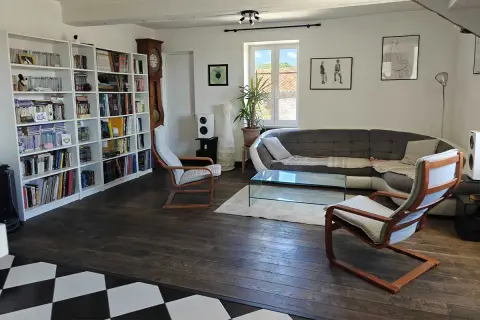 Salon moderne avec bibliothèque, canapé, table basse et fauteuils. Une démarche ergonomique pour un confort optimal.