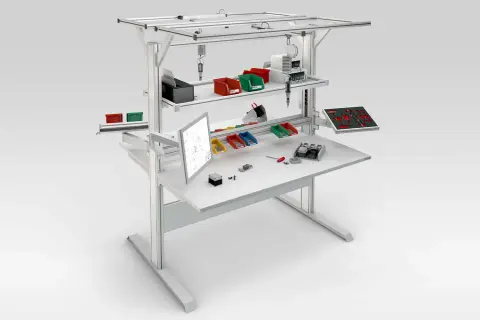 Poste aménagé avec écran, bacs de rangement colorés, outils et composants pour un travail organisé.