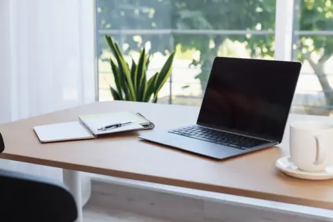Bureau avec ordinateur portable, carnet et stylo. L'obligation employeur fournir ordinateur est respectée.