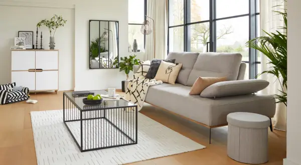 Salon moderne au style épuré avec canapé gris, table basse noire et meuble blanc.