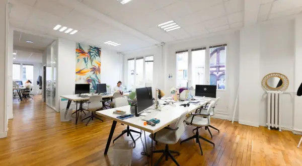 Un bureau moderne avec des postes de travail, des ordinateurs et une décoration murale colorée. L'accueil du bureau est bien organisé pour le planning.
