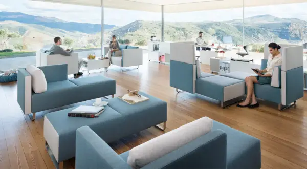 Un espace convivialité entreprise moderne avec des sièges modulables bleus et blancs, offrant une vue panoramique sur des collines verdoyantes.