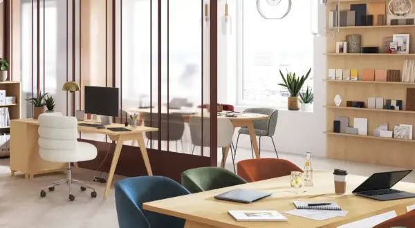 Aménagement espace coworking lumineux avec bureaux en bois, chaises colorées et étagères remplies d'échantillons.