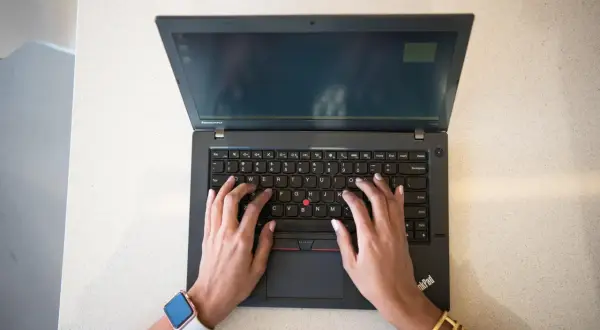 Mains sur un clavier d'ordinateur portable Lenovo, réfléchissant aux 7 critères de choix d'un pc portable.