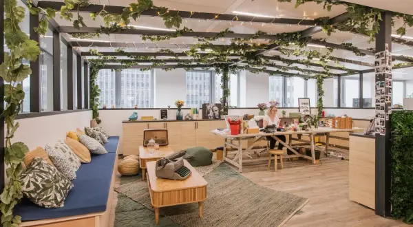 Aménagement locaux start up : un espace de travail lumineux et végétalisé, avec une femme travaillant à son bureau.