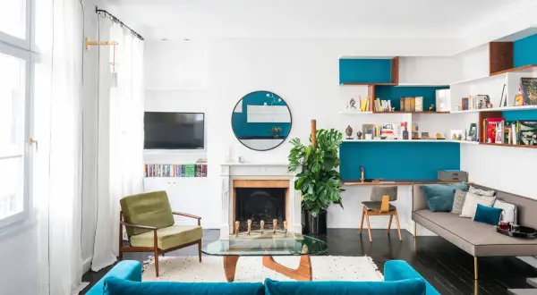 Un coin salon moderne avec canapé bleu, fauteuil vert, étagères murales turquoise et bureau intégré. Idées pour que mettre dans un coin de salon.