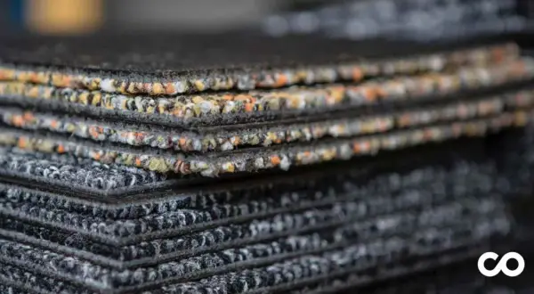 Échantillons de moquette empilés, montrant la texture et les couleurs variées. Une vision claire de la durée de vie d'une moquette.