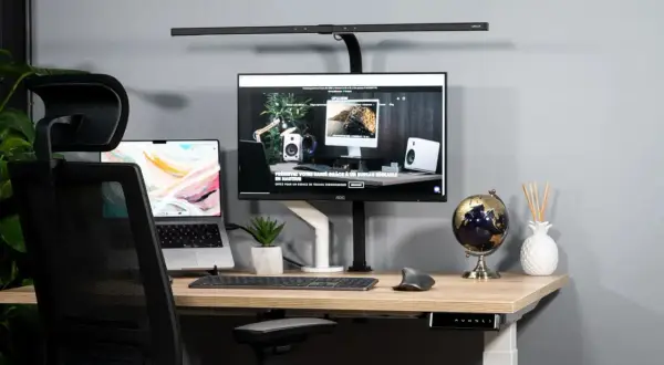Bureau moderne pour aménager un espace de télétravail ergonomique. Ordinateur portable, écran, clavier, souris, et lampe de bureau.