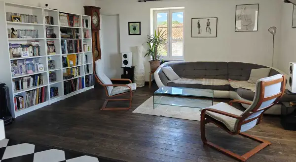 Salon moderne avec bibliothèque, canapé, table basse et fauteuils. Une démarche ergonomique pour un confort optimal.
