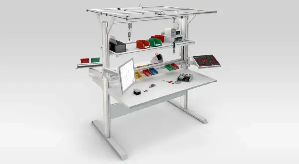 Poste aménagé avec écran, bacs de rangement colorés, outils et composants pour un travail organisé.