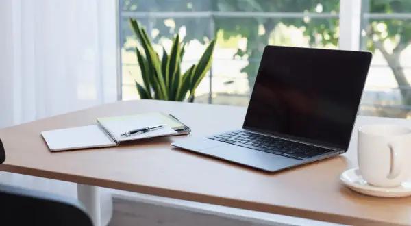 Bureau avec ordinateur portable, carnet et stylo. L'obligation employeur fournir ordinateur est respectée.
