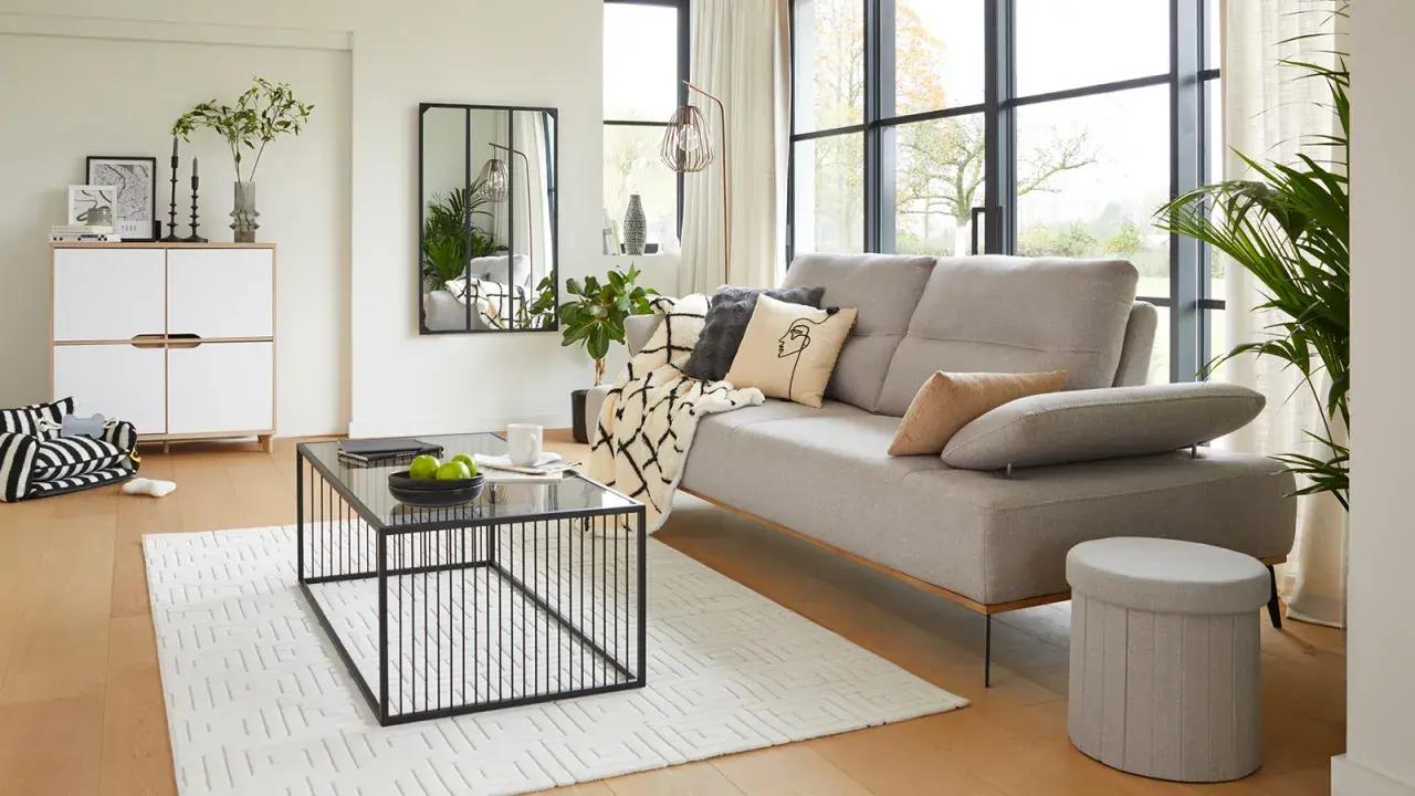 Salon moderne au style épuré avec canapé gris, table basse noire et meuble blanc.