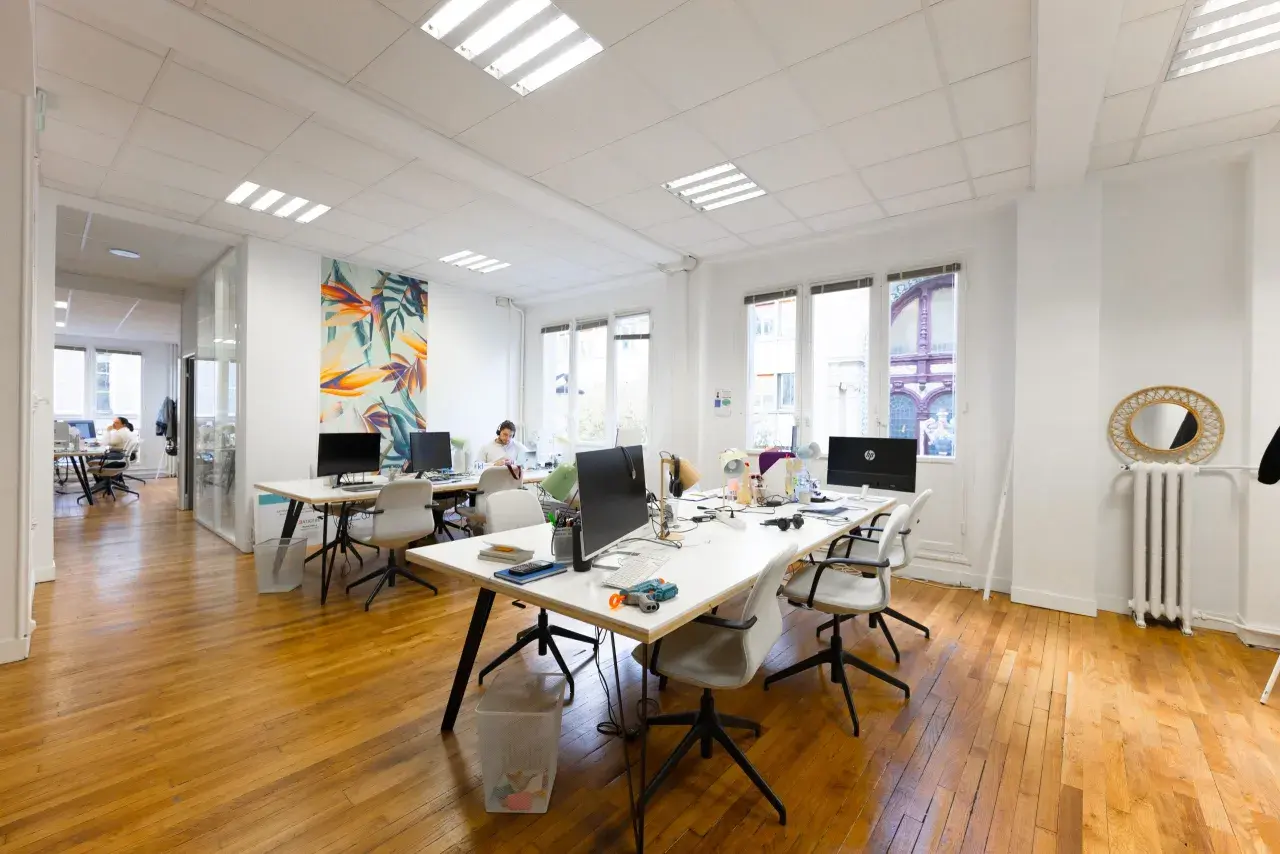 Un bureau moderne avec des postes de travail, des ordinateurs et une décoration murale colorée. L'accueil du bureau est bien organisé pour le planning.