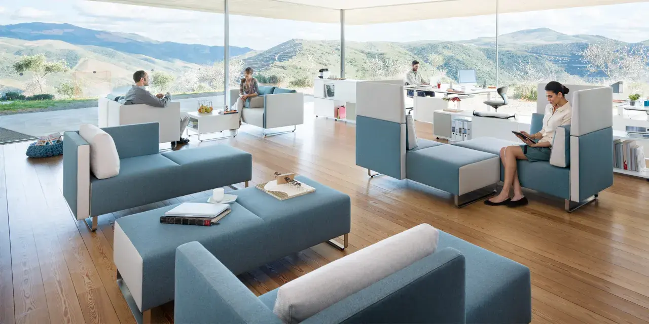 Un espace convivialité entreprise moderne avec des sièges modulables bleus et blancs, offrant une vue panoramique sur des collines verdoyantes.