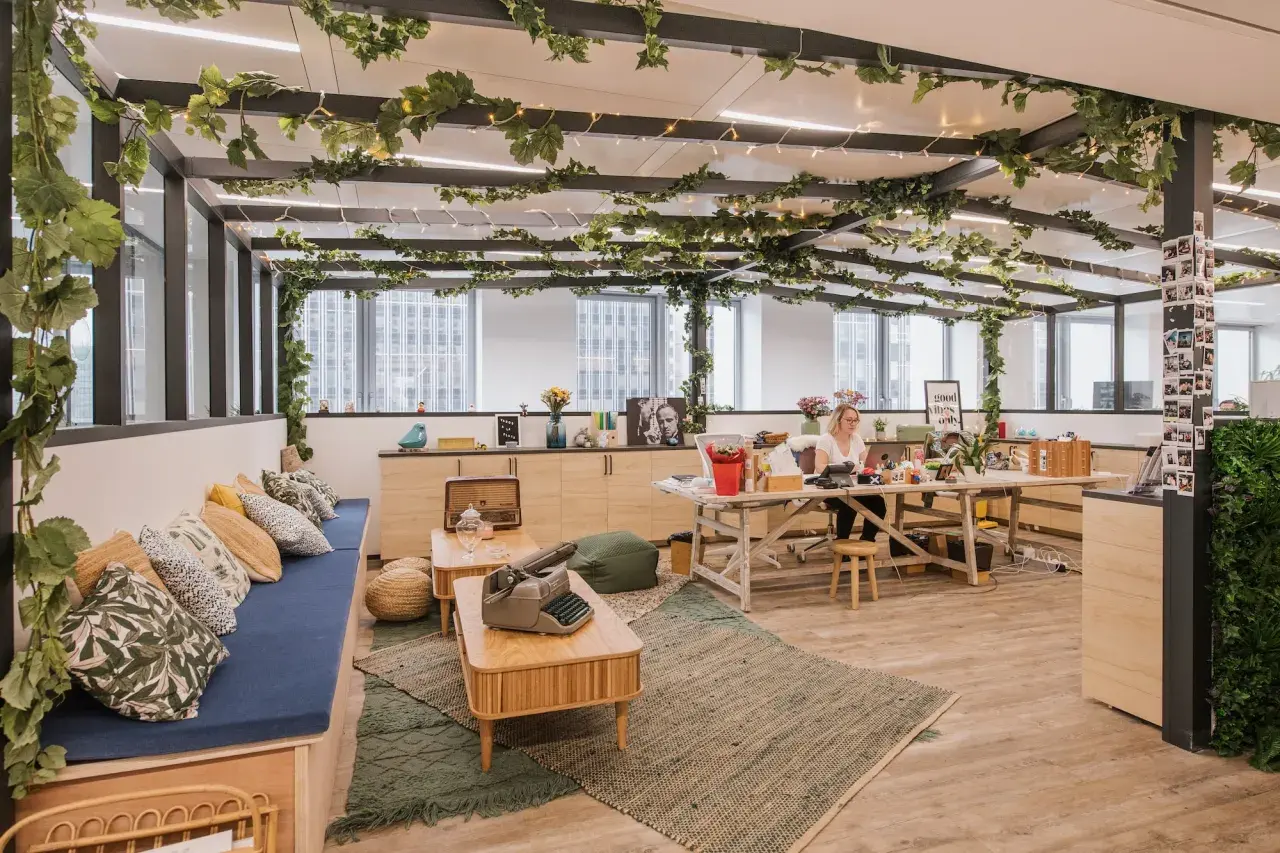 Aménagement locaux start up : un espace de travail lumineux et végétalisé, avec une femme travaillant à son bureau.