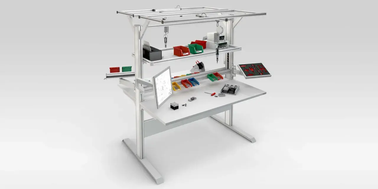 Poste aménagé avec écran, bacs de rangement colorés, outils et composants pour un travail organisé.