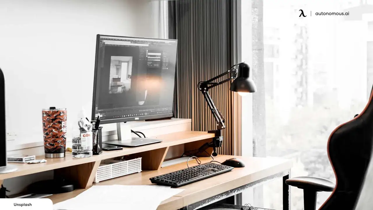 Bureau moderne pour aménager bureau télétravail : écran, clavier, lampe, tasse et chaise ergonomique.