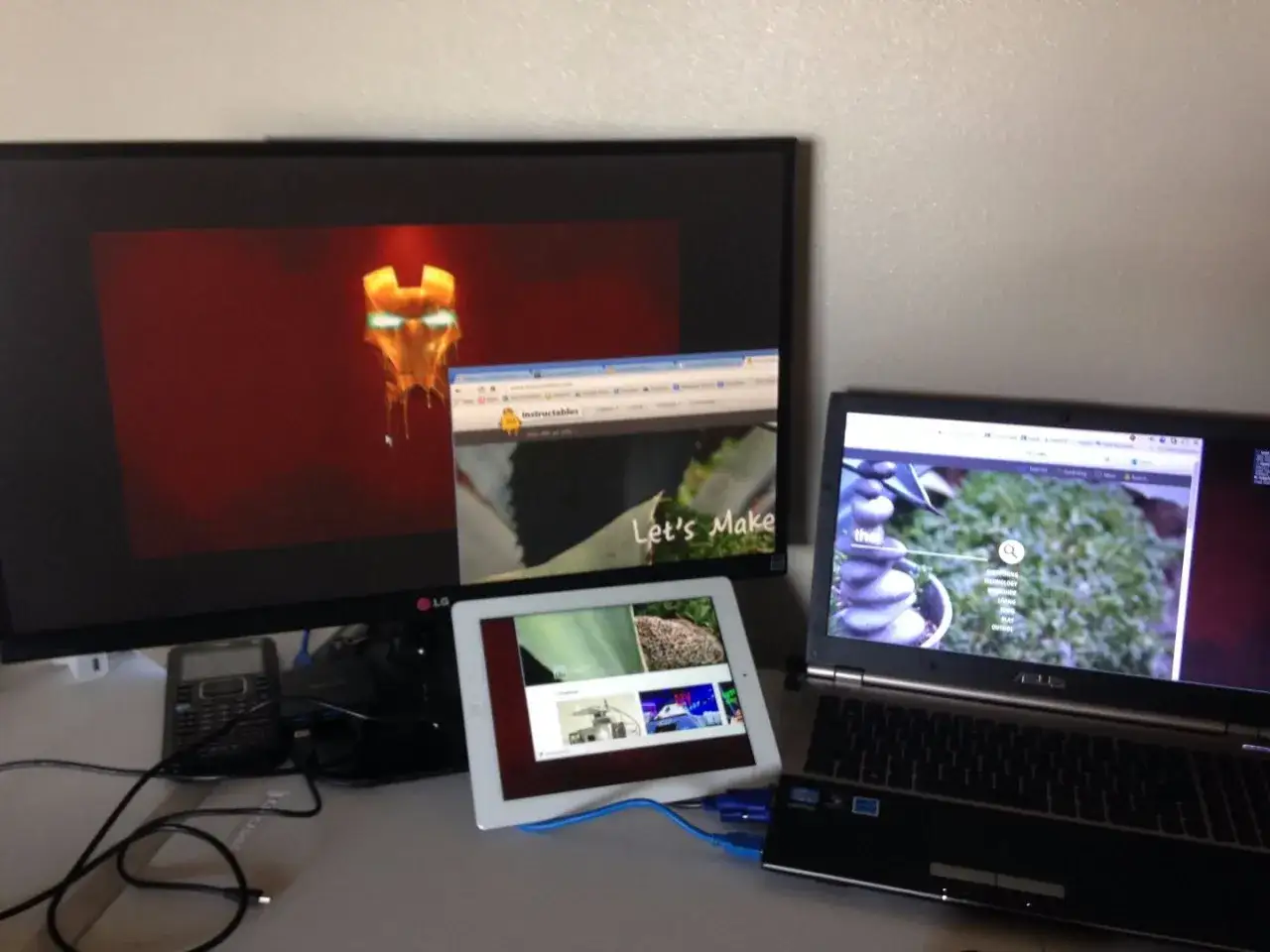 Un bureau avec un écran de PC affichant le masque d'Iron Man, une tablette et un ordinateur portable.