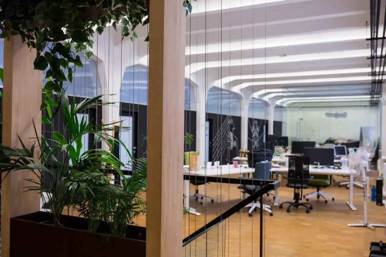 Bureau moderne avec plantes vertes, bureaux blancs et chaises de bureau. Un espace de travail certifié well, lumineux et aéré.
