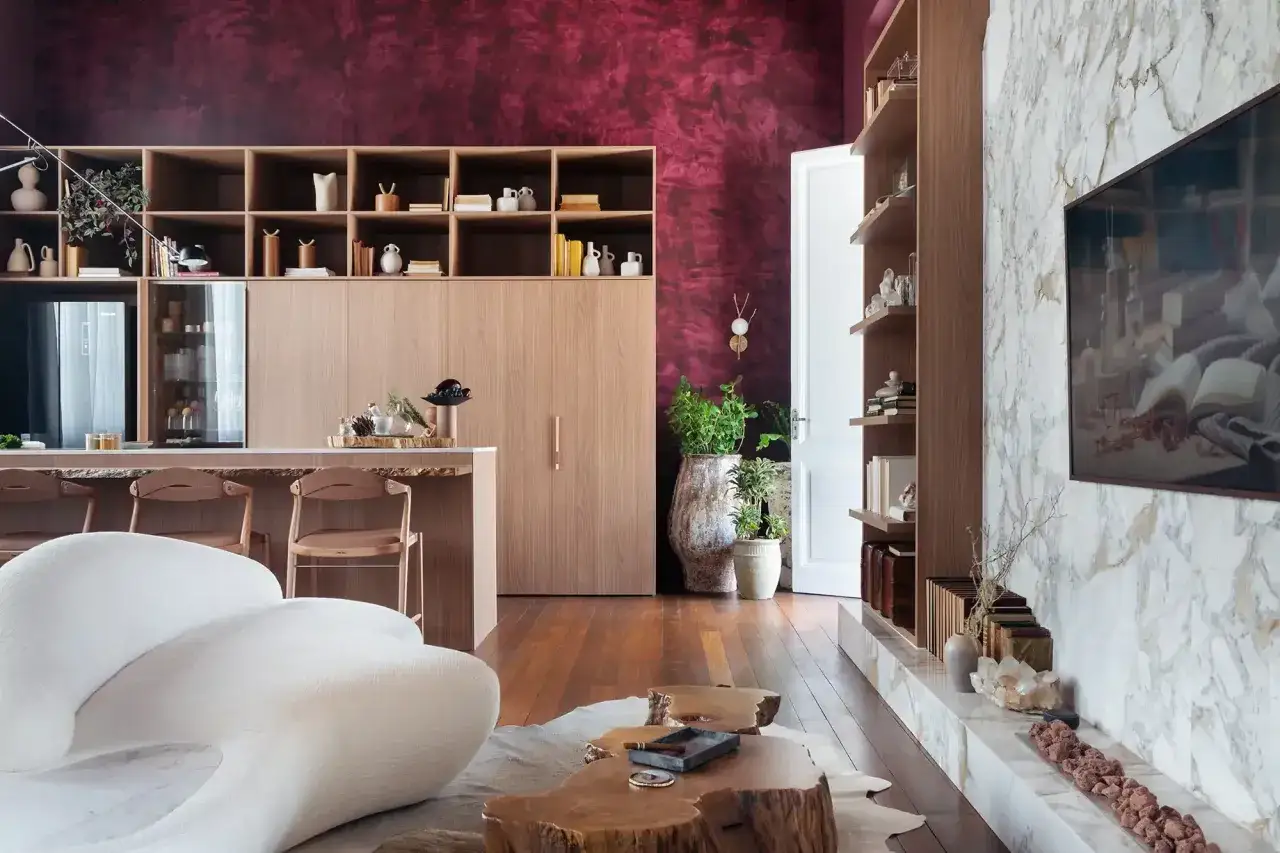 Salon moderne avec mur d'accent couleur marsala pantone, mobilier en bois clair, canap&eacute; blanc sculptural et chemin&eacute;e en marbre.