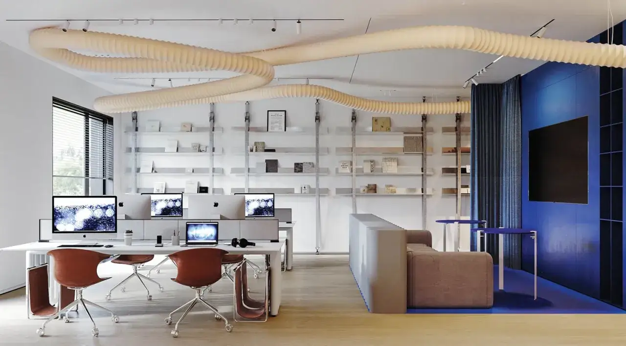 Am&eacute;nagement de locaux professionnels : bureaux modernes avec postes de travail, &eacute;tag&egrave;res remplies de livres et un espace d&eacute;tente bleu vif.